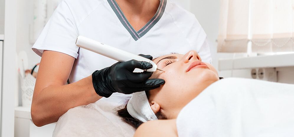 Frau wird in einer Hautarztpraxis vom Hautarzt im Gesicht behandelt - Swift Warzenbehandlung – MVZ Die HautTypen GmbH, Merzhausen